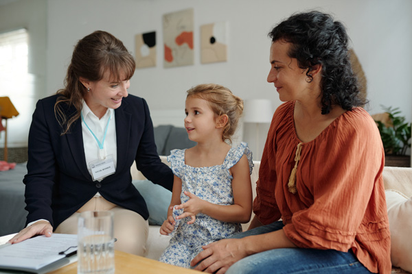 Social worker talking to a child while visiting to their family at home